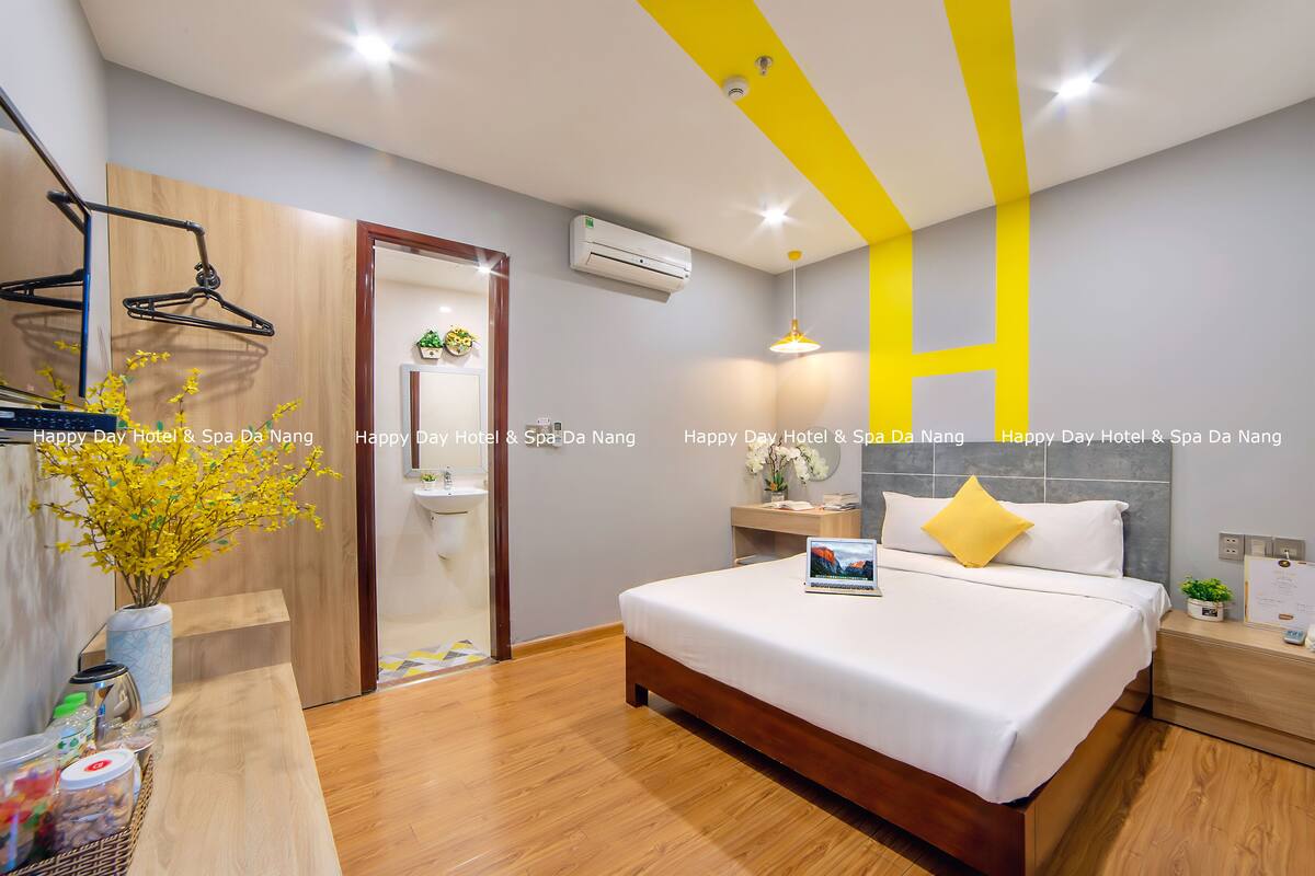 A modern hotel room with a wooden bed, a bedside table, a nightstand, a mirror, and a hanging light fixture.
