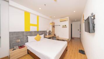 A modern hotel room with a large bed, bedside table, and a TV mounted on the wall.