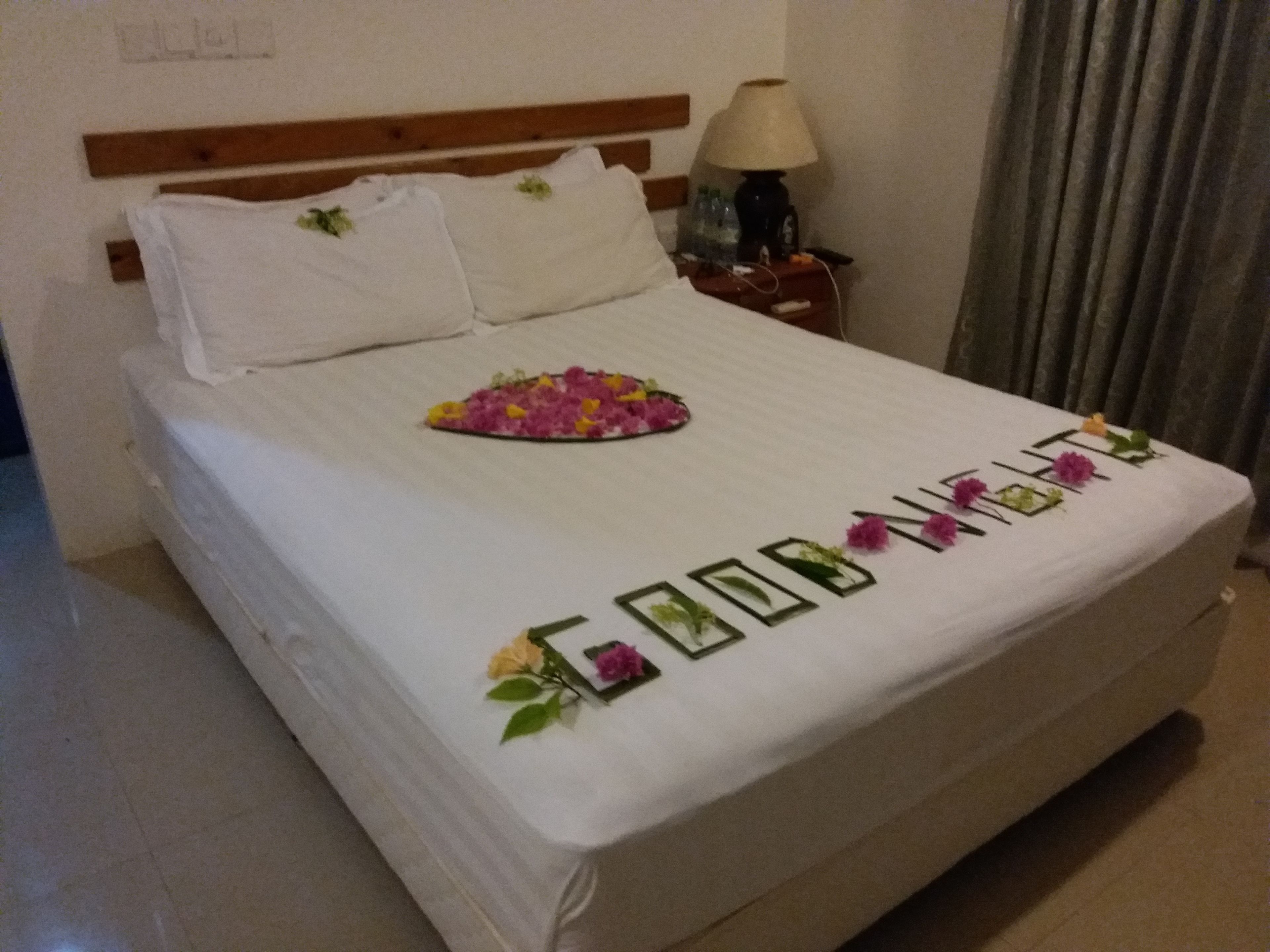 Una cama bien hecha con un arreglo floral y la frase 'GOOD MORNING' bordada en la colcha.