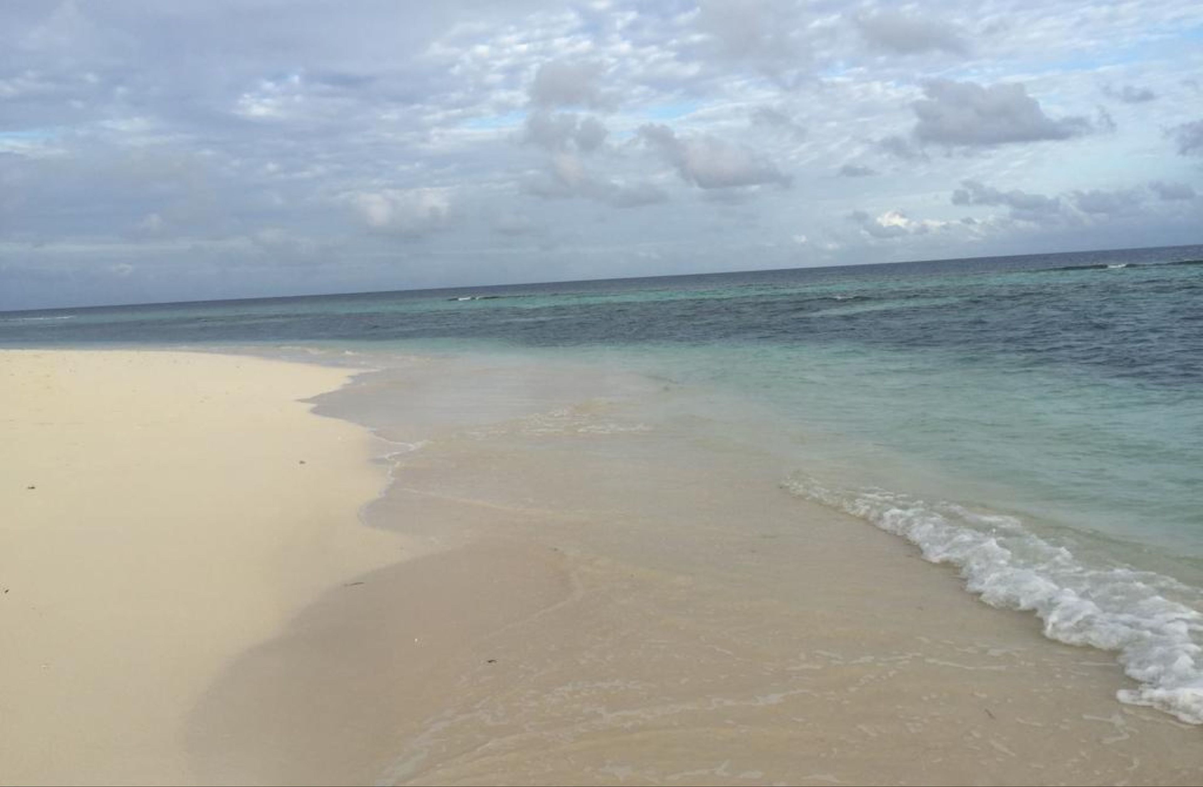 A beach with clear turquoise water and a sandy shore.