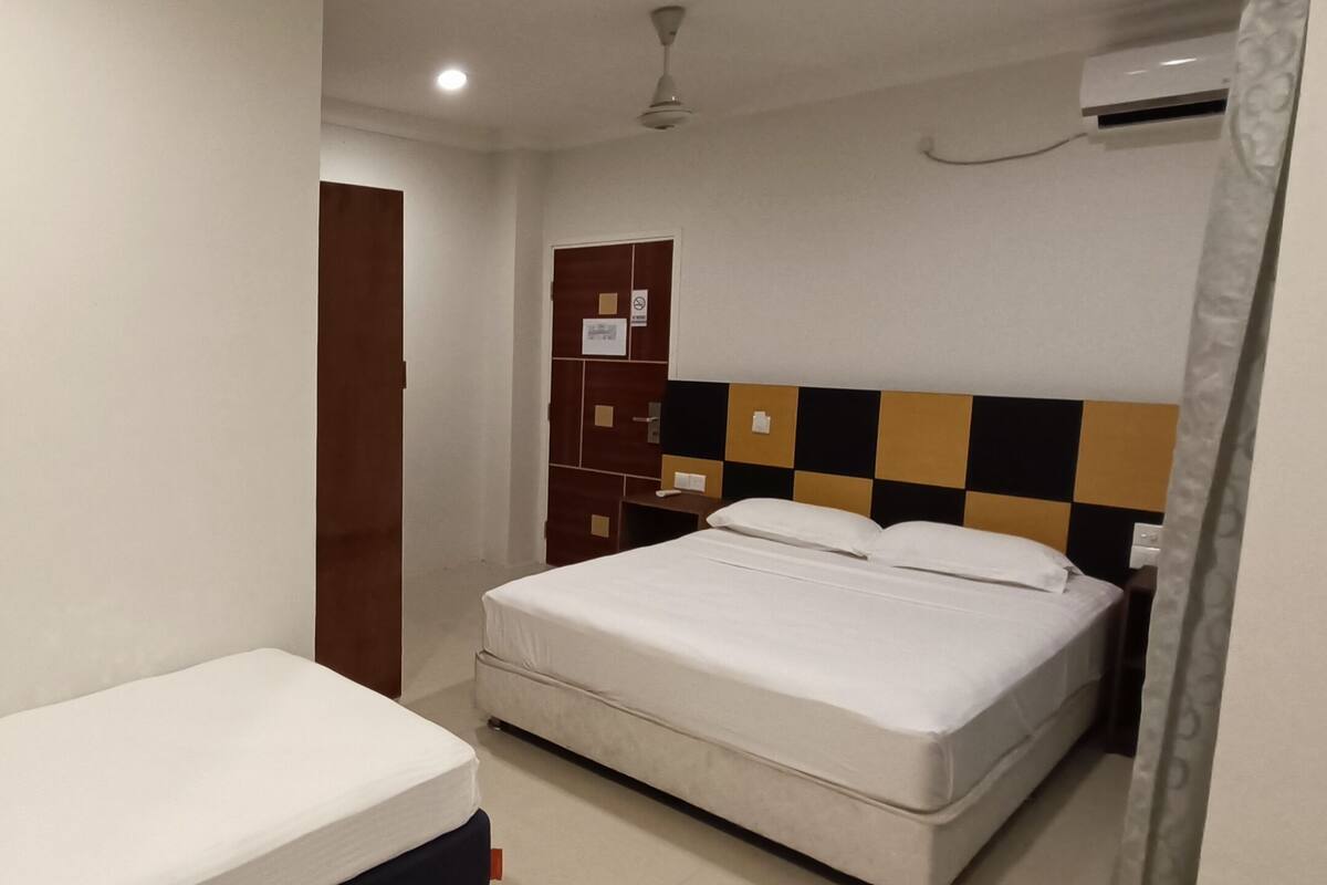 A hotel room with a single bed, a small bedside table, a wardrobe, and a ceiling fan.