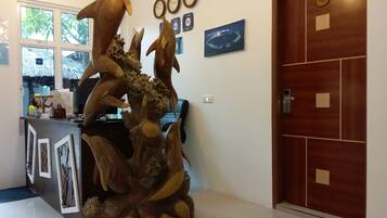 A reception desk with a large wooden sculpture, a clock, and a door with a number plate.