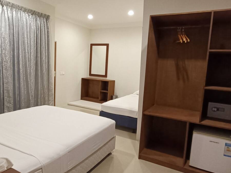 Una habitación de hotel con cama, armario, espejo y un refrigerador pequeño.