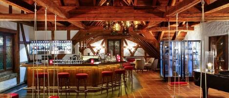 Un rústico espacio bar con vigas de madera, una barra y taburetes.