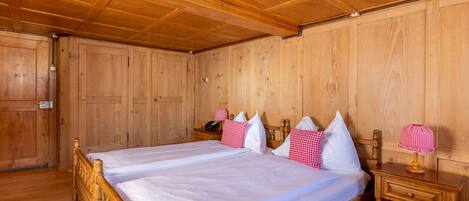 A wooden-paneled room with a large bed, two bedside tables, and a wooden wardrobe.