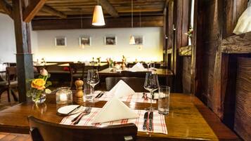A restaurant with wooden tables set for dining, featuring a checkered tablecloth, wine glasses, and cutlery.