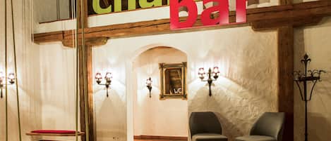 Bar de chalé con vigas de madera, un banco rojo y dos sillas.