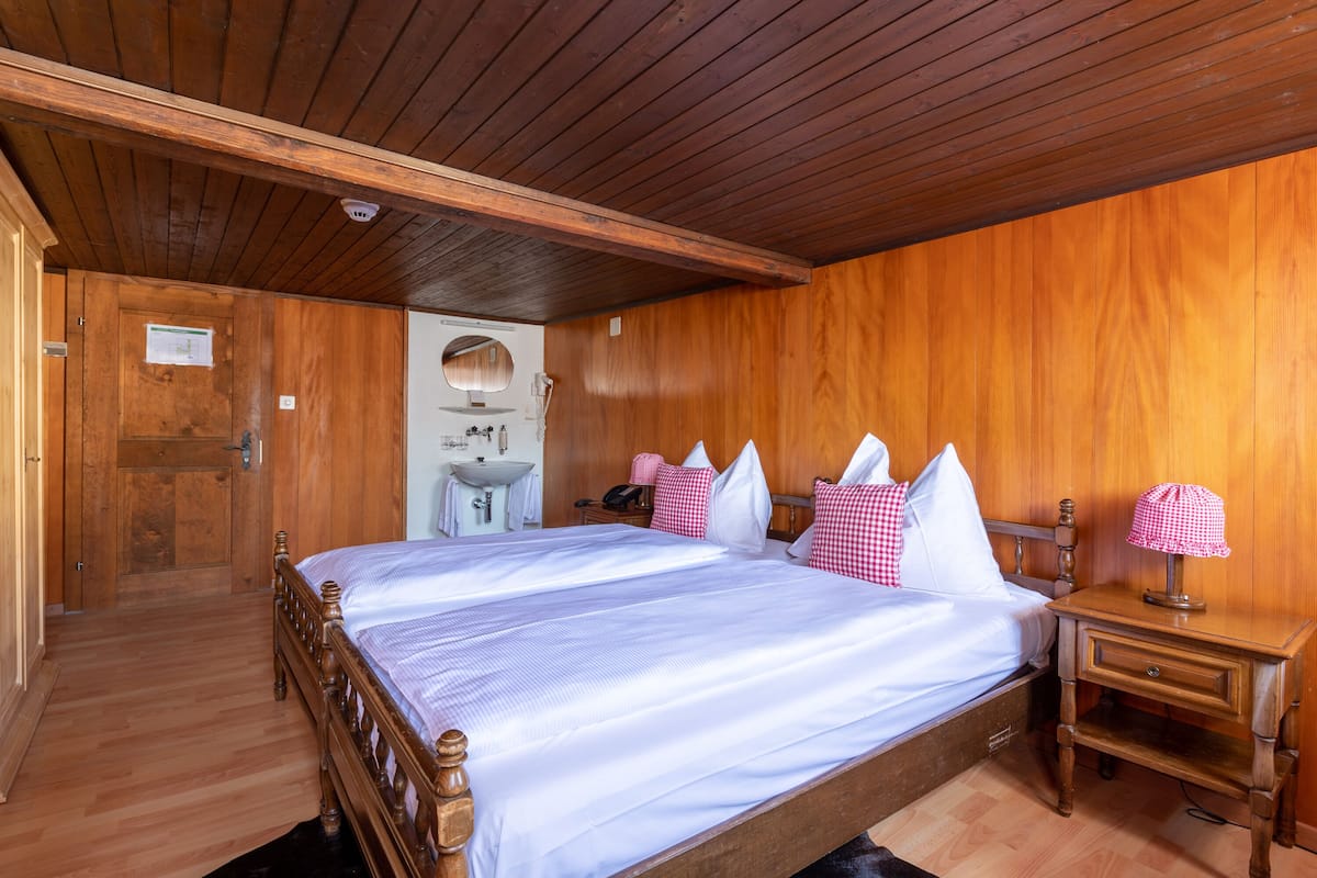 Une chambre à coucher aux murs lambrissés, avec un grand lit, une table de chevet, un miroir et une porte donnant sur une autre pièce.