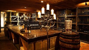 A bar area with wooden furniture, a candelabra with candles, and wine bottles on shelves. - Swiss-Chalet Merlischachen - Historik Chalet-Hotel Lodge (Kuessnacht)