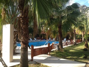 Una piscina al aire libre, sombrillas, sillones reclinables de piscina