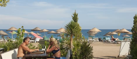 Aan het strand, ligstoelen aan het strand, parasols, een strandbar