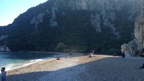 Una playa de guijarros con montañas al fondo.