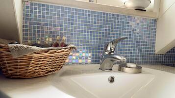 A bathroom with a white sink, a chrome faucet, and a blue mosaic tile backsplash.