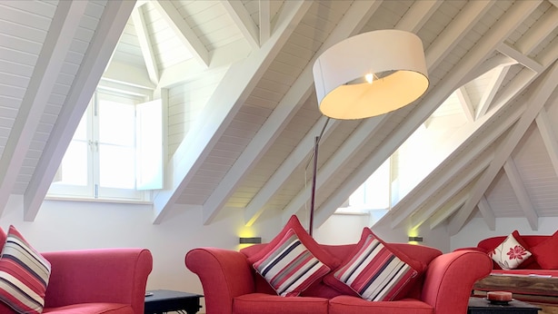 A modern loft with red sofas, a large white ceiling fan, and skylights. - Residence Lagos (Lagos)