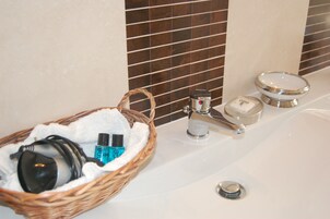 A bathroom with a white sink, a silver faucet, a soap dispenser, and a wicker basket containing toiletries.