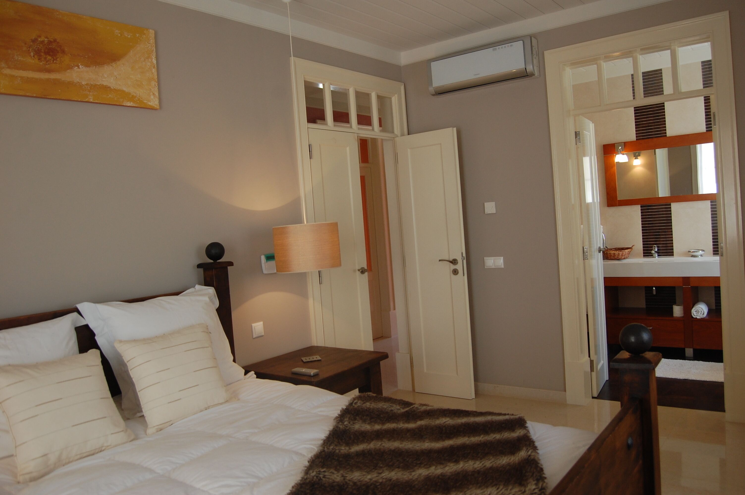 Ein Schlafzimmer mit Bett, Nachttisch, Lampe, Kleiderschrank und Spiegel.
