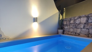 A swimming pool with a stone wall and a light fixture on the wall. - Residence Lagos (Lagos)
