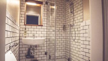 A bathroom with a glass shower enclosure, a sink, and a toilet.