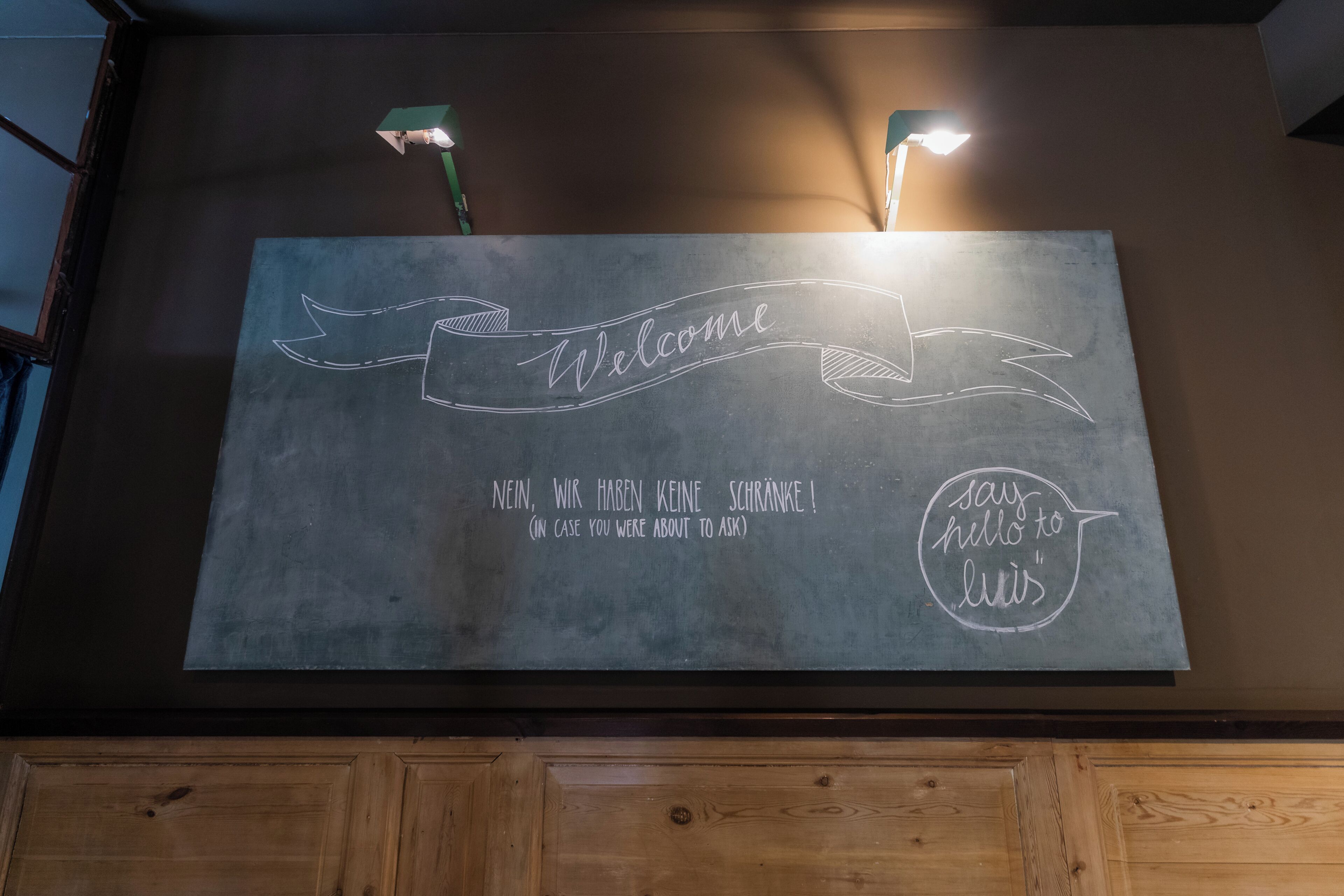 A welcome sign with a ribbon banner and a speech bubble saying 'say hello to Luis'.