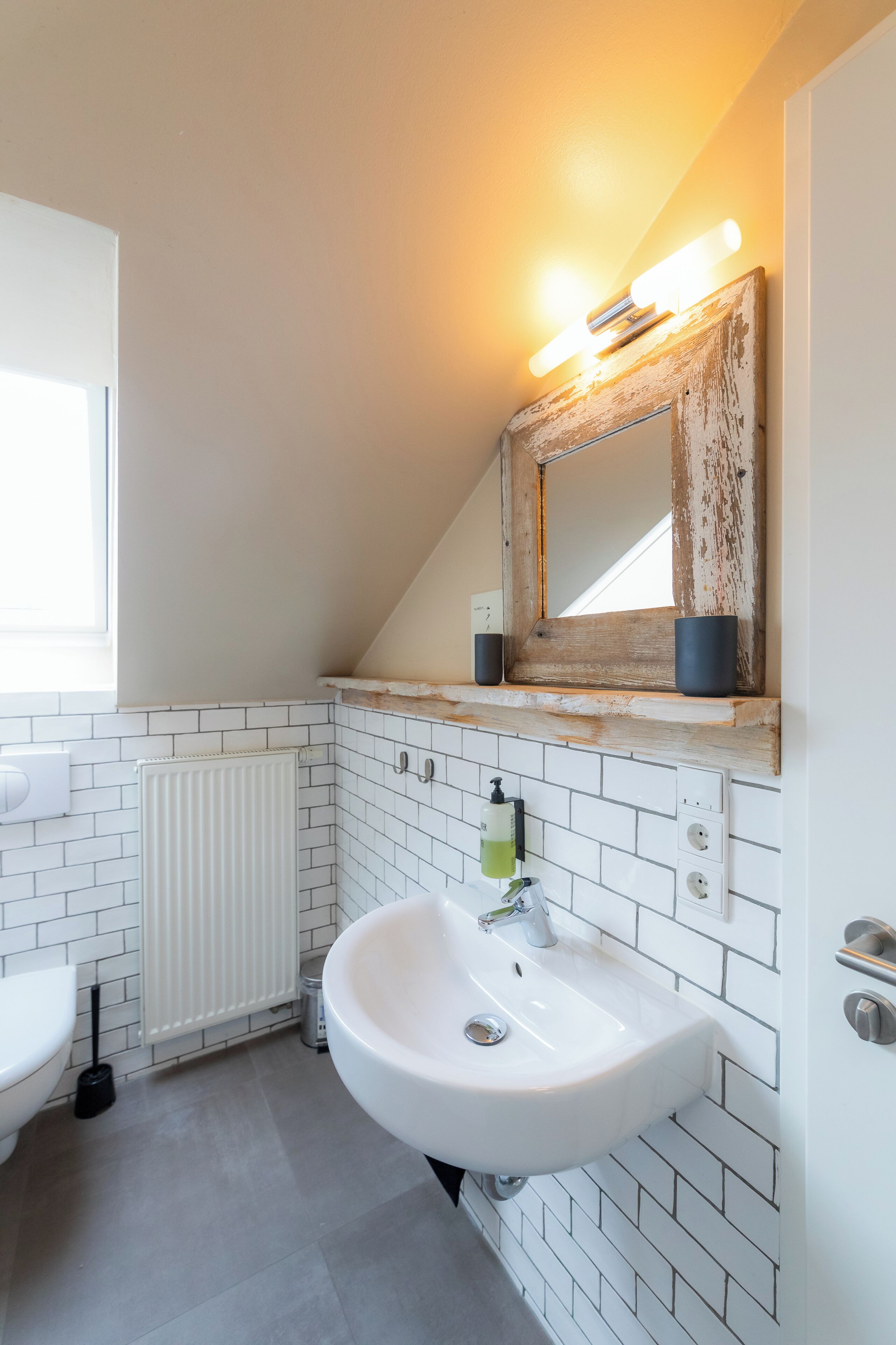 Un baño con un lavabo blanco, un espejo, un perchero para toallas y una ventana.