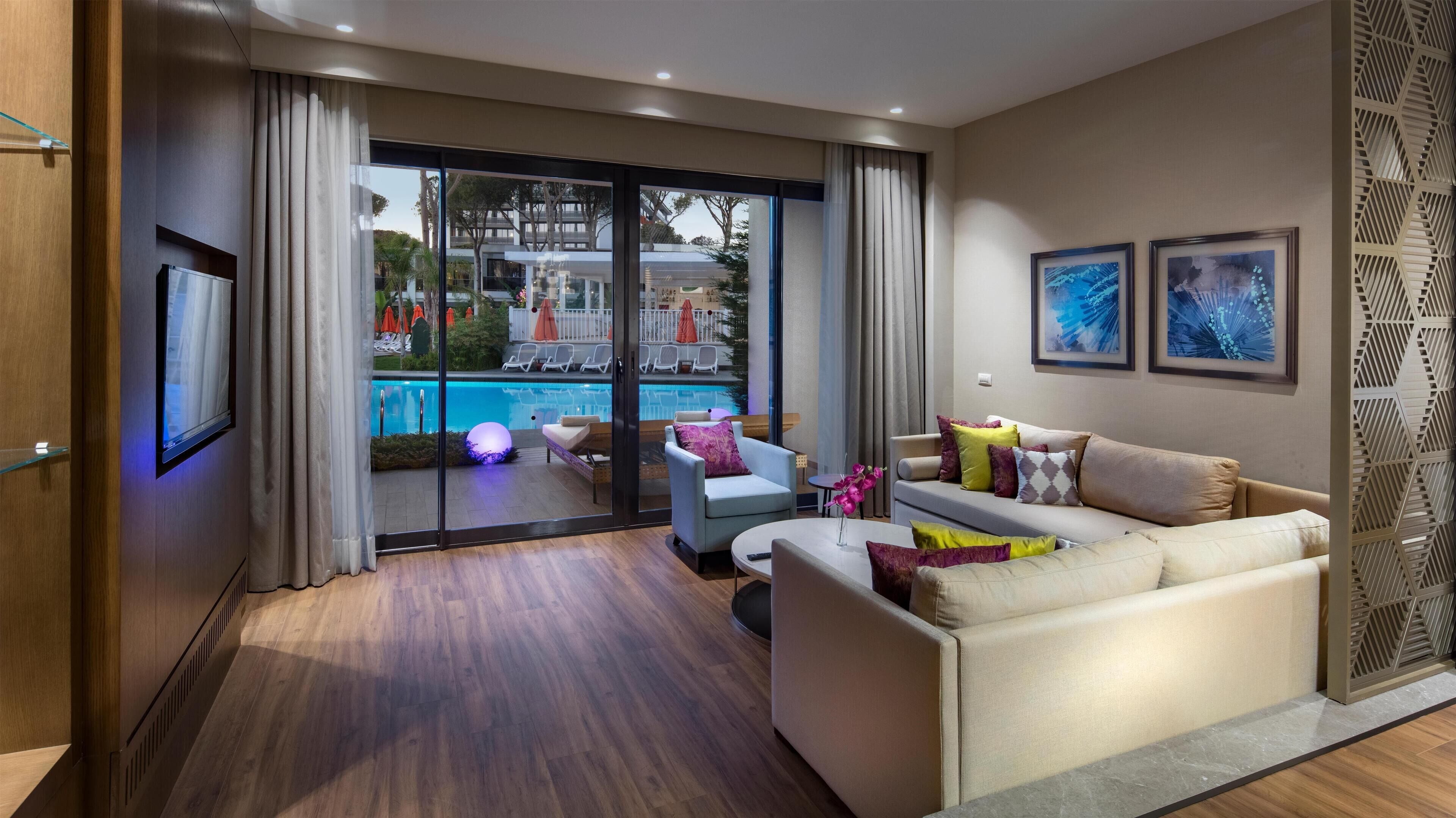 Un salon moderne avec vue sur la piscine, comprenant un canapé, une table basse et un téléviseur.