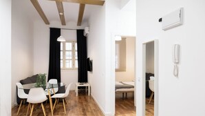 Un espace de vie moderne comprenant un coin repas, un téléviseur fixé au mur et un plafond en bois.