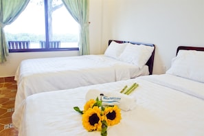 Two single beds in a hotel room with white bedding and a window with curtains. - The Beach House Resort (Ho Chi Minh City)