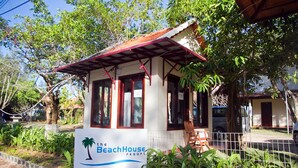 En lille, etetages bygning med rødt tag og et skilt, der viser "The BeachHouse Resort".