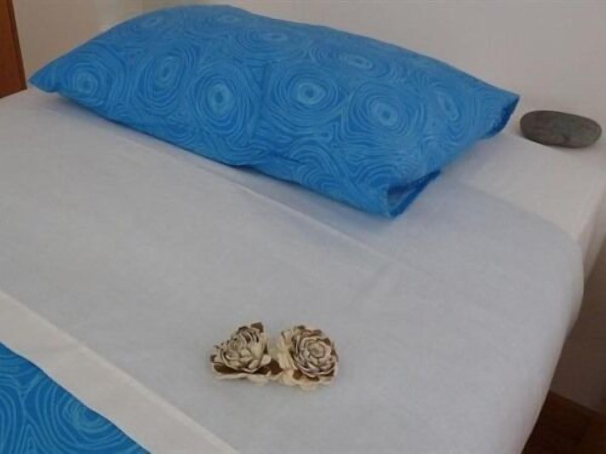 A bed with a blue patterned pillow and a white bedspread.