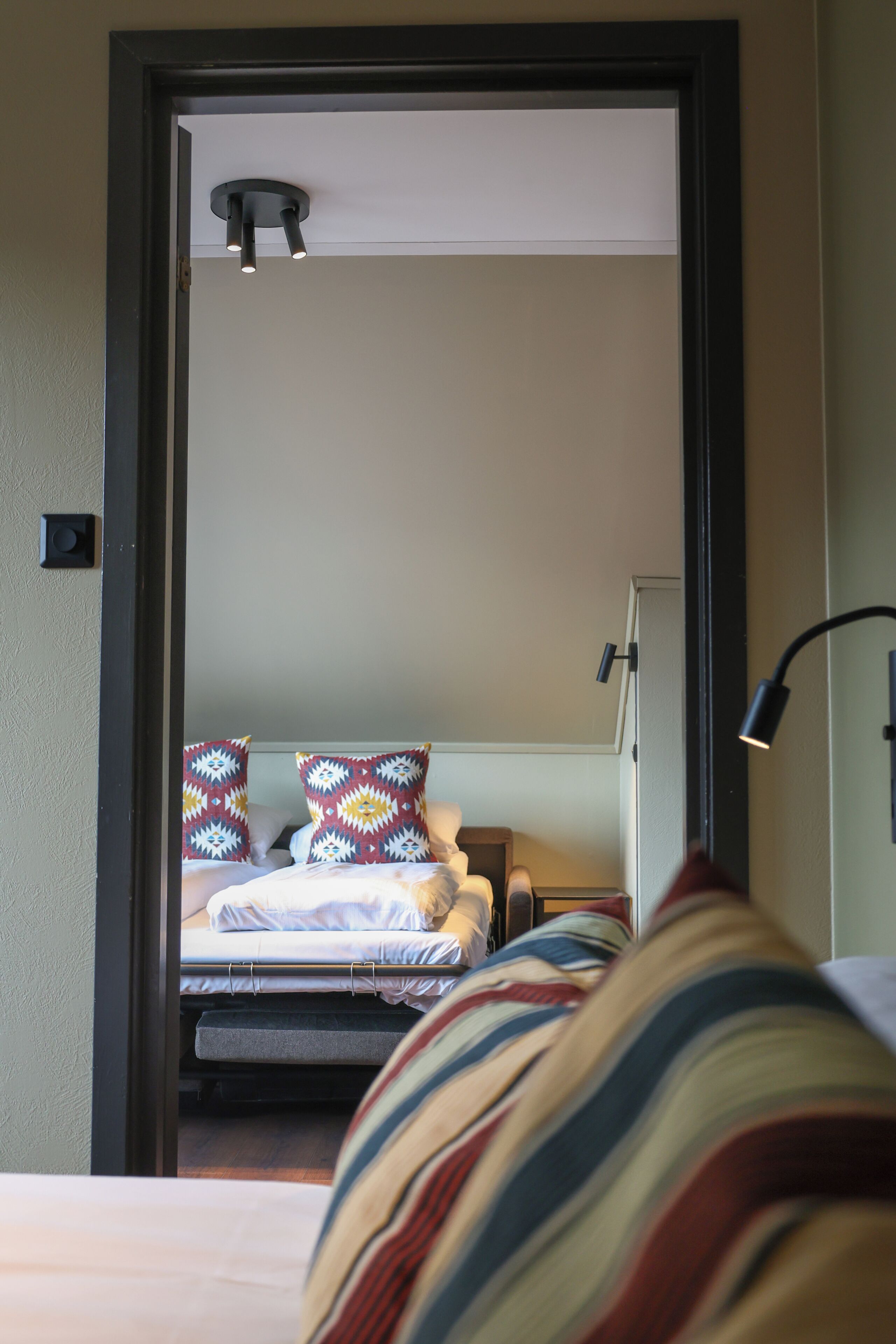 A bedroom with a bed, pillows, a bedside table, and a lamp.
