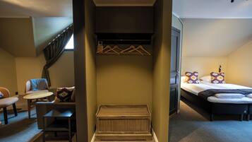 Quarto com cama, mesa pequena, cadeira, banco, armário e janela.