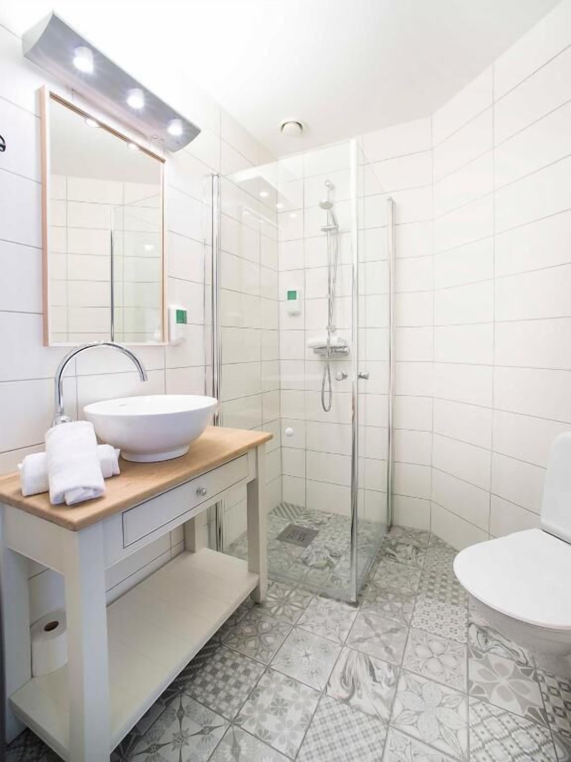 A modern bathroom with a white sink, mirror, and shower.
