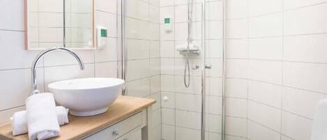 A modern bathroom with a white sink, mirror, and shower.
