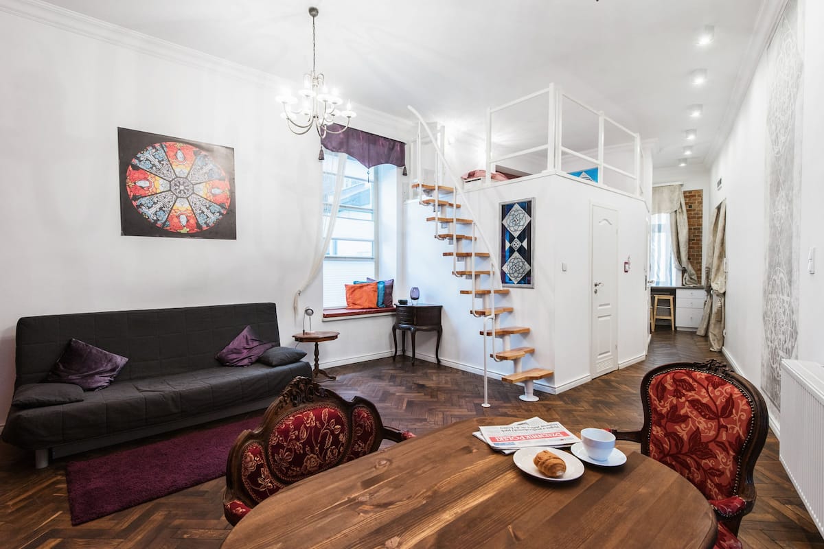 Uma sala de estar moderna com uma mesa de jantar de madeira, um sofá e um candelabro.
