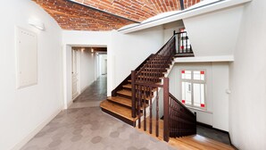 A modern interior with a wooden staircase, white walls, and a brick ceiling. - EchoDom 3 Apartments (Kraków)