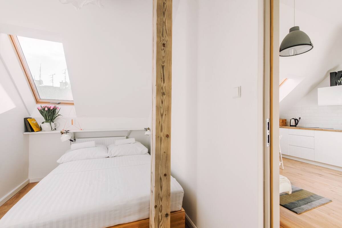 Quarto com cabeceira de madeira, claraboia e vista para a cidade.