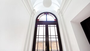 A hallway with a black-framed arched doorway leading to a bright room. - EchoDom 3 Apartments (Kraków)