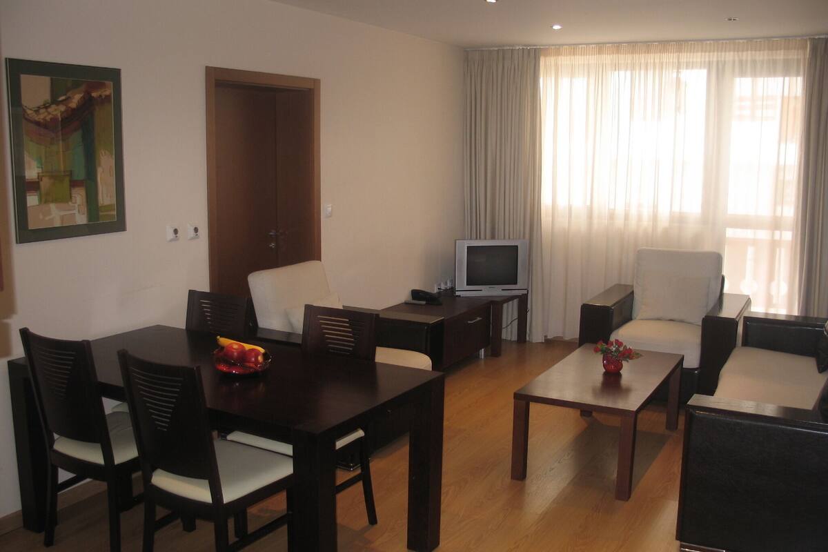 A living room with a dining table, chairs, a TV, and a sofa.