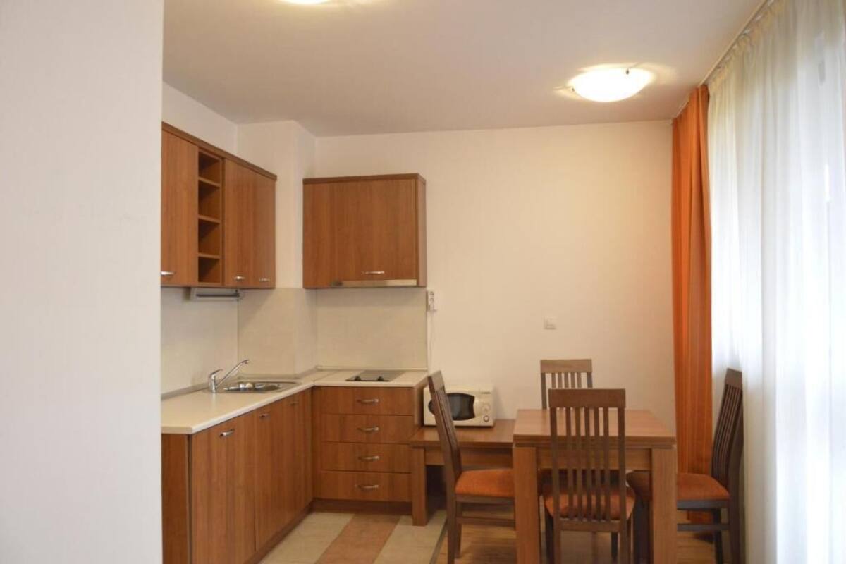 A compact kitchen with wooden cabinets, a microwave, and a dining table with chairs.