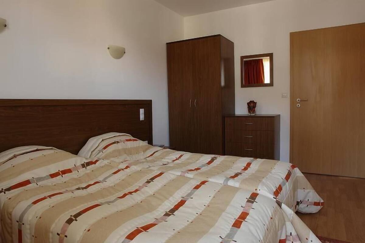 Un dormitorio con cama, armario, espejo y puerta.
