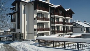 A multi-story hotel with balconies, a snow-covered ground, and a clear sky. - Winslow Elegance Hotel (Bansko)