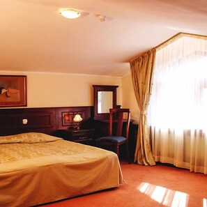 A hotel room with a bed, a desk, a chair, a lamp, a mirror, and a window with curtains. - Hotel Elina (Chepelare)