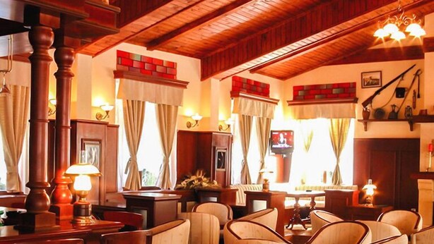A cozy, rustic interior with wooden beams, a fireplace, and comfortable seating. - Hotel Elina (Chepelare)