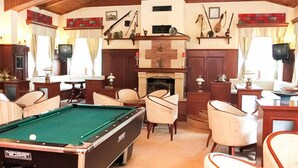 A cozy room with a pool table, comfortable seating, a fireplace, and wooden beams on the ceiling. - Hotel Elina (Chepelare)