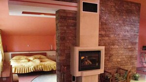 A modern living room with a fireplace, a bed, and a sofa. - Hotel Elina (Chepelare)