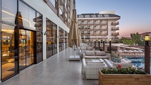 Un hotel moderno con zona de piscina, asientos exteriores y vista a la piscina.