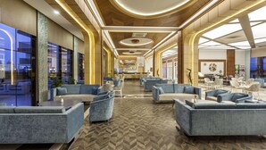 Un vestíbulo amplio con muebles modernos, una zona de bar central y grandes ventanales que ofrecen vistas del paisaje urbano.