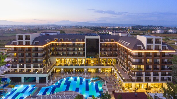 Un hotel con varios pisos, piscina y vistas del paisaje circundante.