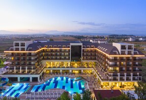 A hotel with multiple floors, a swimming pool, and a view of the surrounding landscape. - Glamour Resort & Spa - All Inclusive (Manavgat)