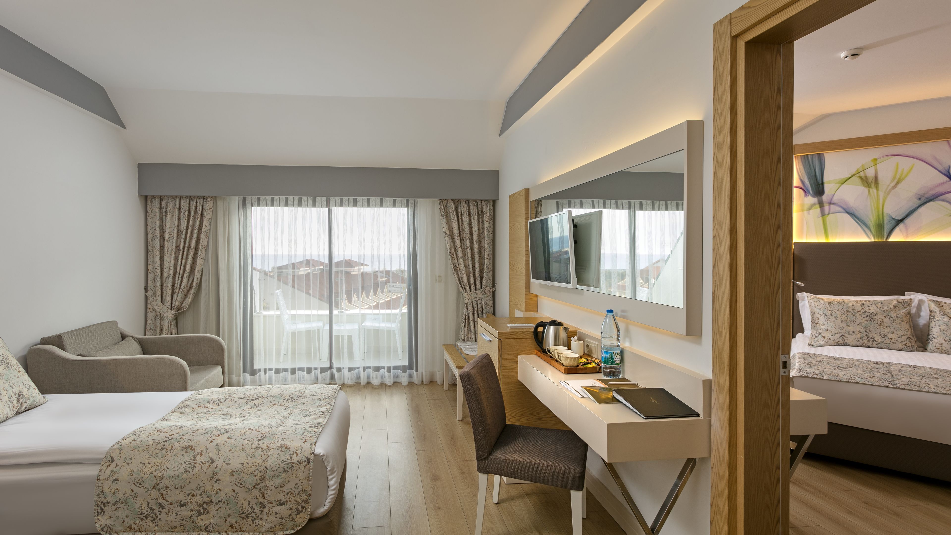 Una habitación de hotel con cama, escritorio con silla, televisor y vistas al exterior.